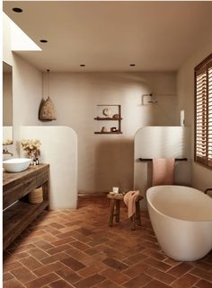 a bathroom with brick flooring and large bathtub next to a sink in the corner