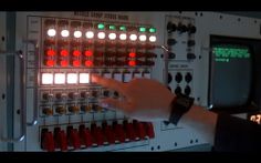 a person pointing at a control panel with red and green lights in the middle of it