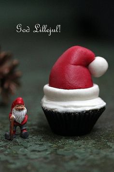 a cupcake with a santa clause hat next to a small figurine