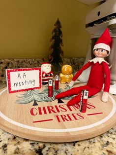 an elf sitting on top of a counter next to some candy bars and a sign