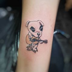 a small tattoo of a dog with a guitar in its paws, on the arm