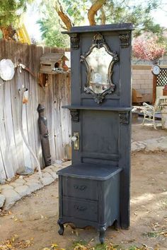 an antique black cabinet with mirror on top