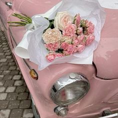 a bouquet of flowers sitting on the hood of a pink car