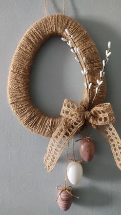 a wreath hanging on the wall with two eggs attached to it and twine string