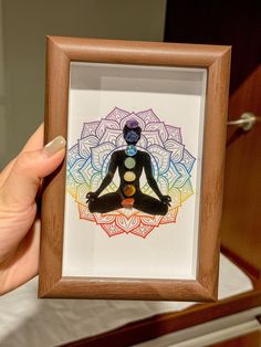 a person holding up a framed artwork with chakragrams in the center on it