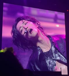 a man with his mouth open standing in front of a large screen at a concert