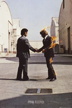 two men shaking hands with each other in the middle of an empty parking lot on fire