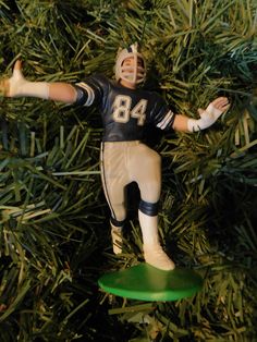 a football player ornament hanging from a christmas tree with green frisbee