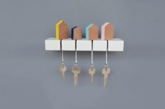 five keys hang on a white shelf with four different colored houses hanging from it's sides