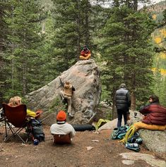 several people sitting on the ground near some trees