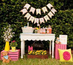 a pink and yellow birthday party is set up in front of a hedge with decorations