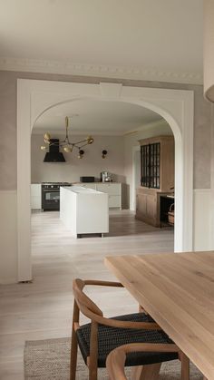 an open kitchen and dining room area with wood flooring, white walls and ceiling