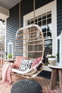 a hanging chair with pillows on the front porch