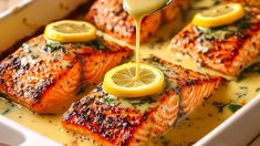 salmon being drizzled with lemon and parsley