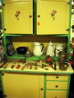 a green and yellow cabinet filled with kitchen utensils on top of a counter