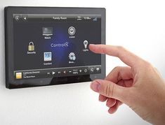 a person pointing at a touch screen on a wall mounted device with buttons and icons