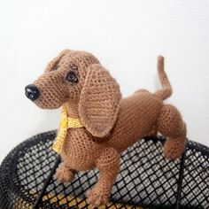 a crocheted dog sitting on top of a wire basket