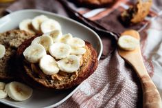 banana bread with peanut butter and sliced bananas on a plate next to a glass of orange juice