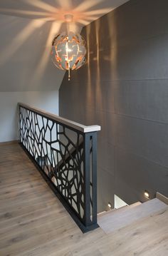 a light fixture hanging from the side of a wall next to a wooden floor and railing