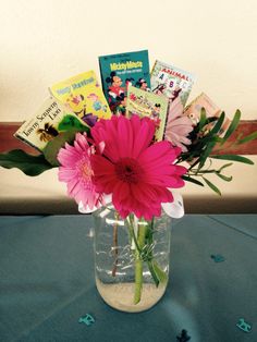 a vase filled with flowers and books on top of a blue tablecloth covered table