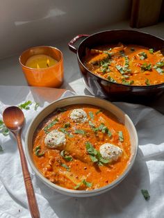 there is a bowl of soup with meatballs in it and a spoon on the side