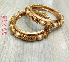 Most elegant gold and pearls classics bangles. The brass base and micro gold polished finish with  pearls strung around  it. It's the replica of real gold bangles. Easy to pair with any ensemble. ** P.S: non returnable product. Please ask any question if you have related to this product before purchasing as returns for size, color or weight etc are not covered. Buyer is responsible for return shipping cost in these cases. Gold Pearl Bangle For Gift, Gold Pearl Bangle As Gift, Gold Pearl Bangle Perfect As A Gift, Gold Pearl Bracelet With Gold Beads For Wedding, Festive Gold Pearl Bracelet Gift, Elegant Bangle With Pallu For Diwali, Traditional Gold Bangle Pearl Bracelet, Gold Bangle With Round Beads For Wedding, Traditional Gold Pearl Bangle Bracelet