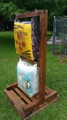 two bags are sitting on top of a pallet in the grass near a fence