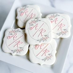 four decorated cookies on a white plate with pink and gray lettering that says mr and mrs