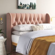 a bed with a pink headboard and white sheets on top of it in a bedroom