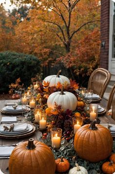 a table set with pumpkins, candles and other fall decorations for an outdoor dinner