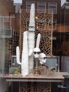 a display in a store window with fake cacti and sunglasses on it's head