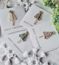 four christmas tree brooches sitting on top of each other next to some flowers