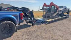 a blue truck is towing a tractor behind it