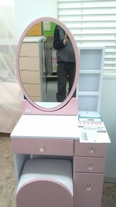 a pink vanity with a mirror on top of it and a person in the background