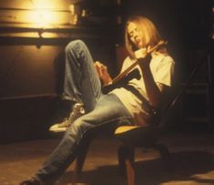 a man sitting on top of a chair holding a guitar