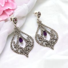 For sale are these gorgeous earrings set in solid silver; they have two sparkling amethyst gemstones. Marcasite gemstones surround the earrings.  The back is hallmarked with '925' to show that they have been made with sterling silver.  Great as a gift or adding a little something extra to an outfit looks great against any skin tone. Wear them with swept-back hair to show it off. This captivating pair arrives in a beautifully presented gift box, adding an extra touch of sophistication to your jew Purple Drop Chandelier Earrings For Formal Occasions, Elegant Sterling Silver Earrings With Gemstone Accents, Ornate Sterling Silver Chandelier Earrings For Formal Occasions, Ornate Sterling Silver Chandelier Earrings For Formal Events, Ornate Purple Pierced Earrings, Silver Diamond Gemstone Earrings For Evening, Elegant Purple Pierced Earrings, Ornate Purple Sterling Silver Earrings, Elegant Amethyst Dangle Earrings