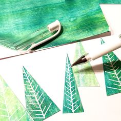 some green trees are painted on white paper with a fountain pen and watercolor brush