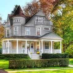 a large gray house sitting on top of a lush green field