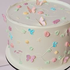 there is a white cake with butterflies on the frosting and icing, along with other decorations