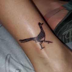 a small tattoo on the leg of a person with a bird on it's arm