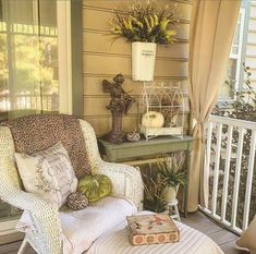 a chair sitting on top of a porch next to a table with flowers and plants