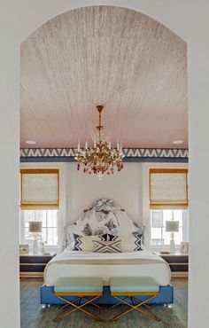 a bedroom with a large bed and chandelier hanging from the ceiling