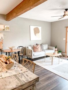 a living room filled with furniture next to a wooden table and white couches on top of a hard wood floor