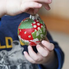 a young boy holding a christmas ornament in his hand