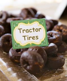 there is a sign that says tractor tires in front of some chocolate donuts on the table