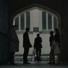 several people are standing in front of an archway