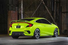 the rear end of a neon green honda civic hatchback parked in front of a barn