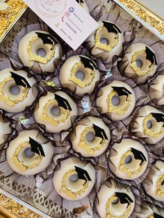 there are many doughnuts decorated with black and gold decorations on display in the box