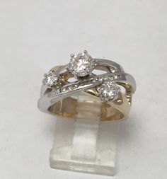 two tone gold and white gold wedding rings with diamonds on each band, set in an acrylic block