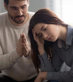 a man kneeling down next to a woman who is praying